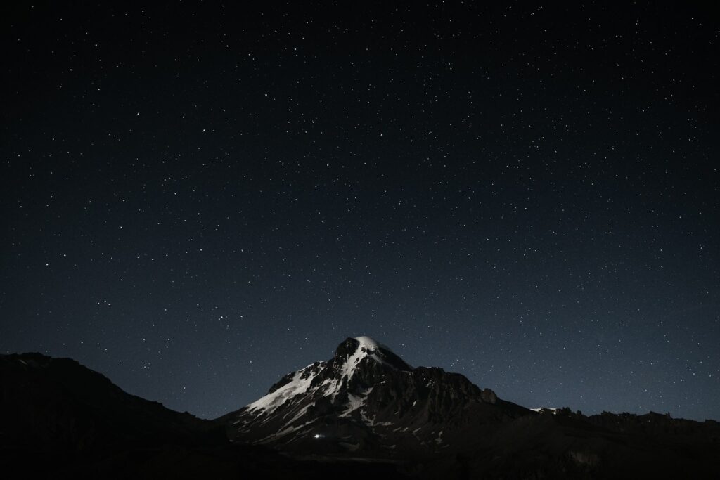 The night sky with stars above a mountain